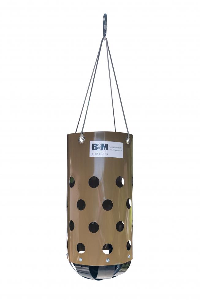 Ein braun Heu Toy, bestehend aus einem braunen Zylinder mit faustgrossen runden Löchern in der unteren Hälfte, aufgehängt an vier grauen Seilen zusammengeführt an einem Karabinerhakenunterer Deckel be